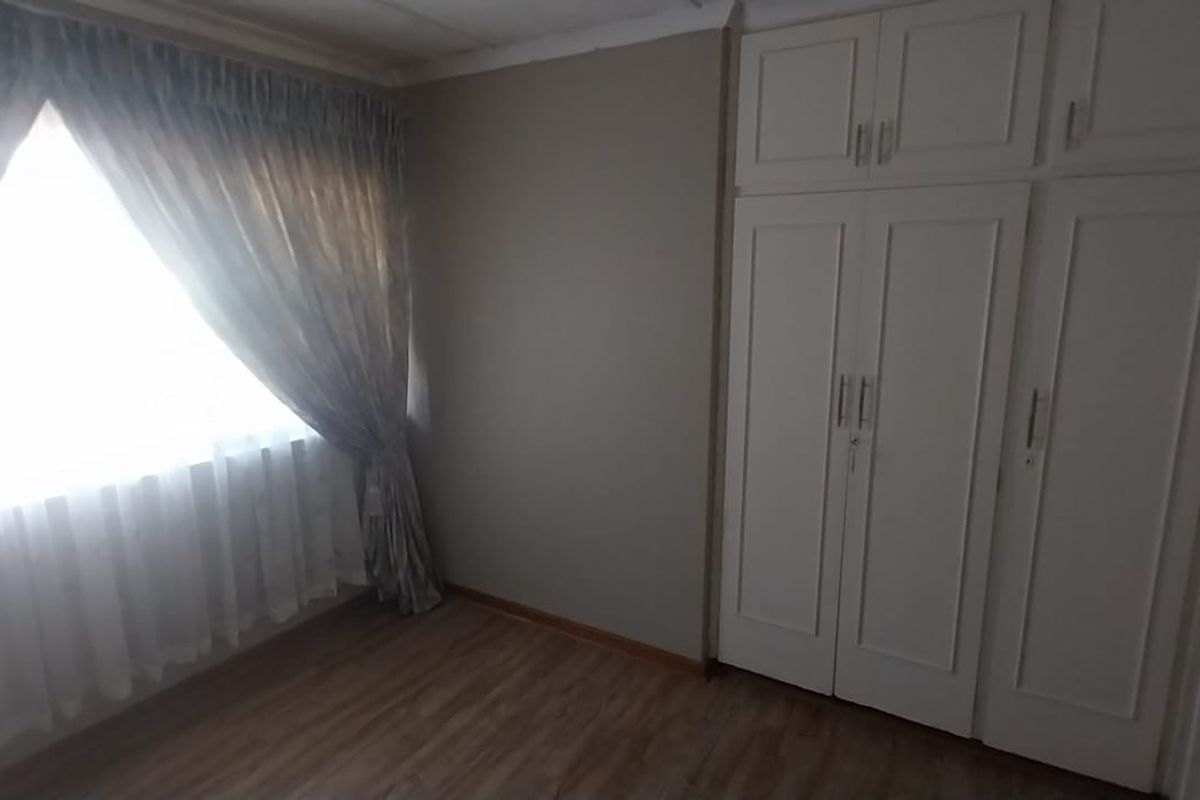 A clean, empty bedroom featuring laminate flooring and ample built-in cupboard storage space.