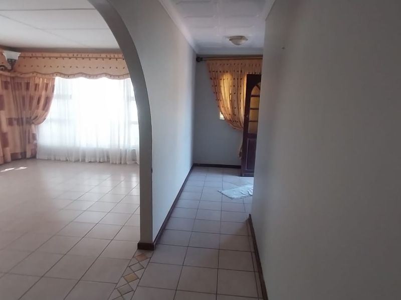 A spacious living area featuring tiled flooring and a distinctive architectural archway, providing an open and bright atmosphere.