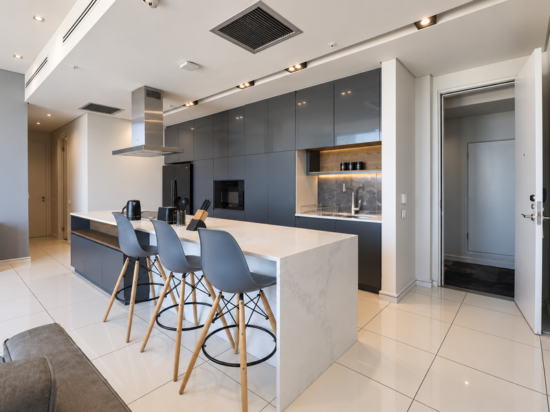 Modern open-plan kitchen featuring high-gloss cabinetry, a large quartz-topped island, integrated appliances, and sleek recessed lighting in a contemporary penthouse setting.
