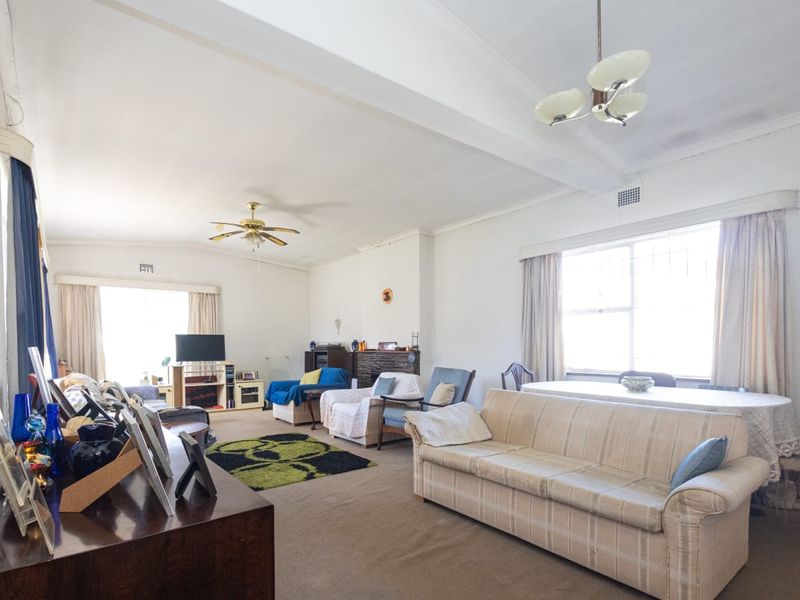 Spacious open-plan living and dining area featuring a fireplace, ceiling fan, and large windows providing natural light.