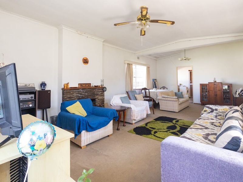 Spacious living room featuring a stone fireplace, ceiling fan, and neutral wall finishes, offering a comfortable layout for family relaxation.