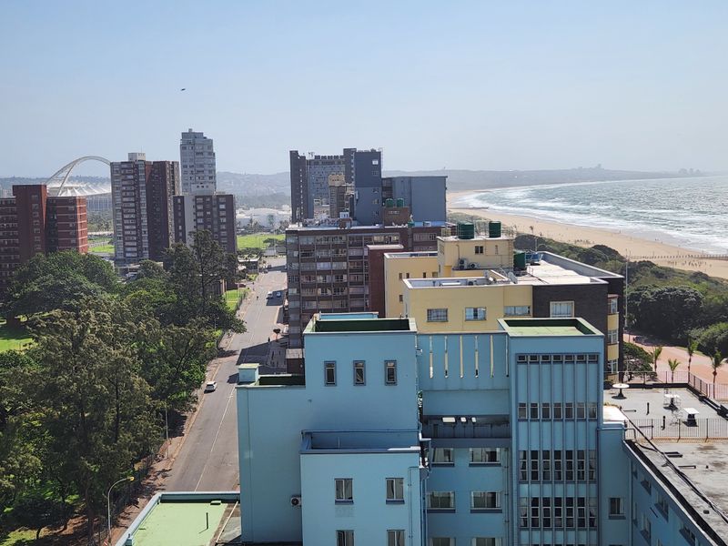 Elevated coastal view overlooking the city skyline, surrounding apartment buildings, and the nearby beach.