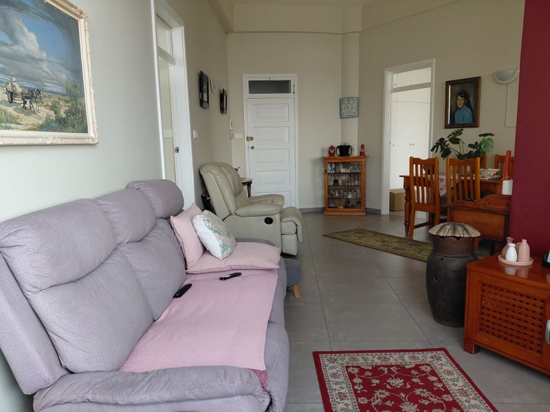 An open-plan living and dining area featuring neutral wall tones and tiled flooring, providing a functional layout with access to adjacent rooms.