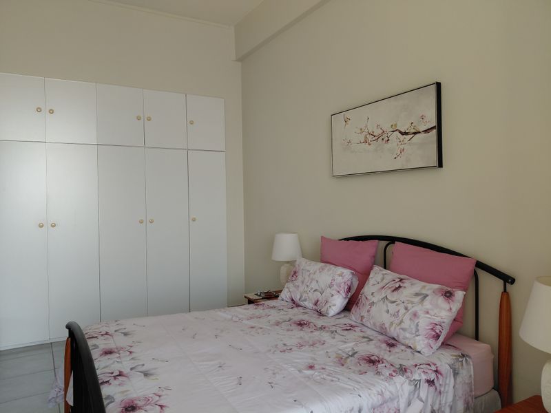 A bedroom featuring a large white built-in wardrobe with ample storage space.