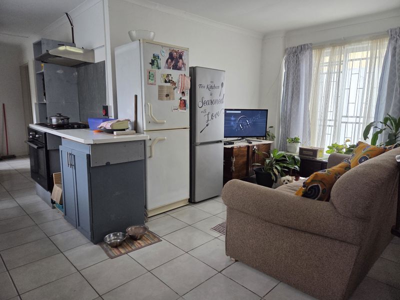 Open-plan living and kitchen area featuring tiled flooring, built-in oven, hob, and extractor fan, offering a functional layout for daily living.