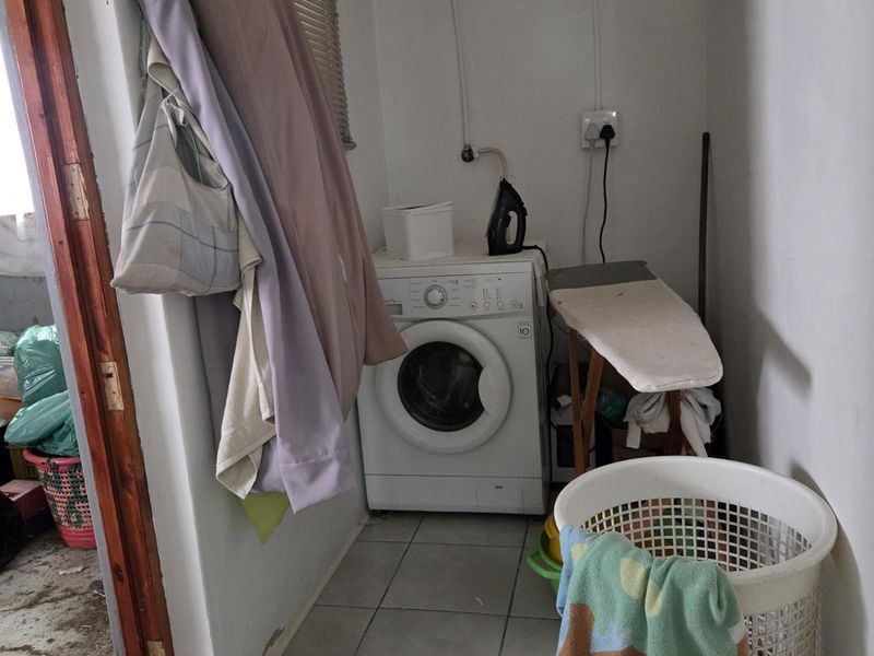 A functional laundry area featuring tiled flooring and dedicated space for laundry appliances, requiring minor maintenance to wall finishes.