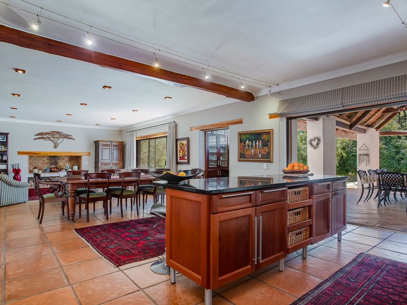 Spacious open-plan living and kitchen area featuring a large island, terracotta flooring, exposed timber beams, and seamless flow to an outdoor patio.
