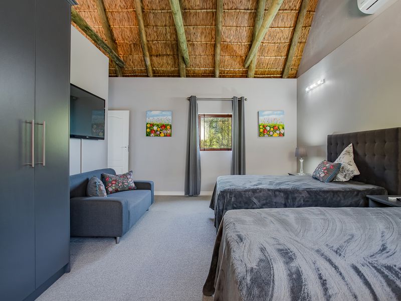 Spacious bedroom featuring a high vaulted thatched ceiling with exposed timber rafters, neutral wall finishes, and a built-in wardrobe.