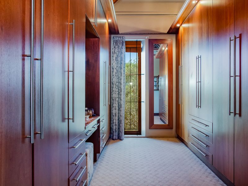 A well-appointed walk-in dressing room featuring extensive custom timber cabinetry, integrated vanity space, and recessed lighting.