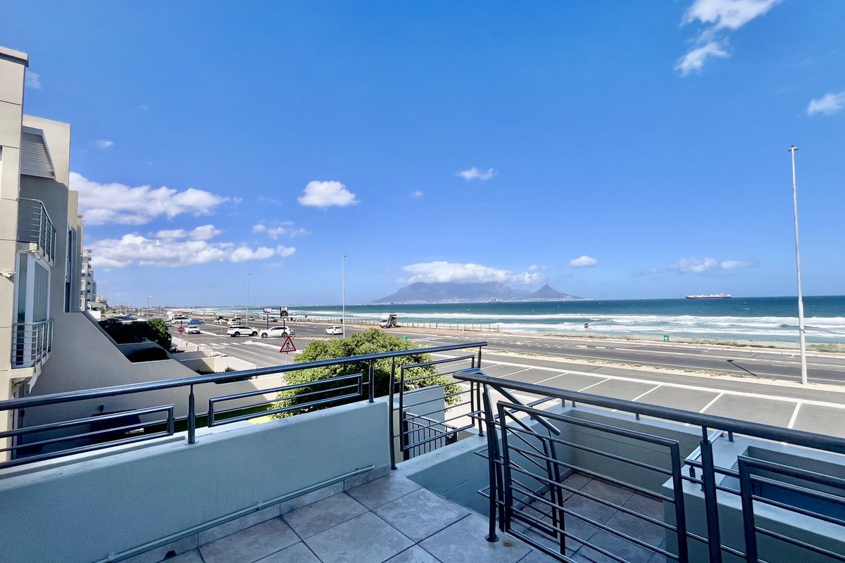Spacious balcony featuring a stainless steel balustrade and tiled flooring, offering panoramic views of the coastline and Table Mountain.