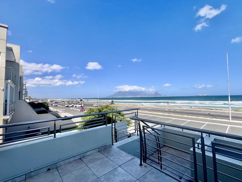 Spacious balcony featuring a stainless steel balustrade and tiled flooring, offering panoramic views of the coastline and Table Mountain.