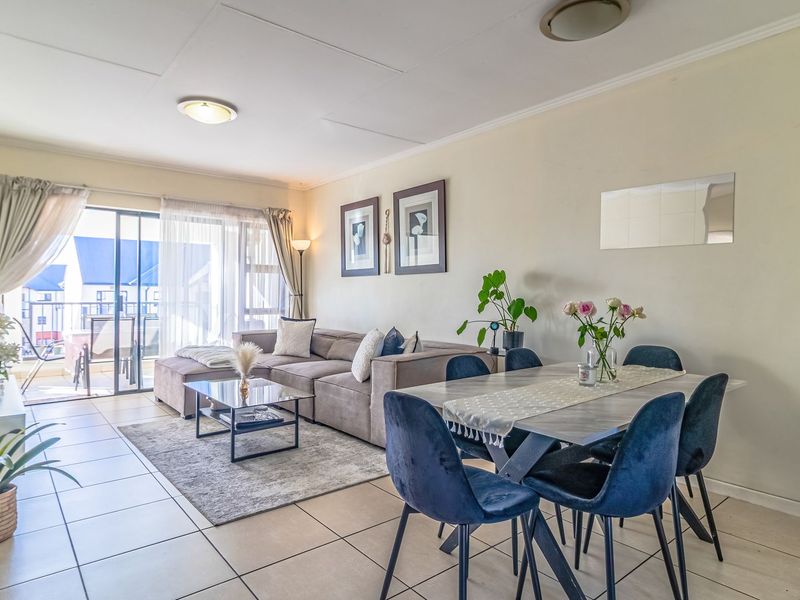 An open-plan living and dining area featuring tiled flooring, neutral walls, and a sliding glass door providing access to an outdoor balcony.
