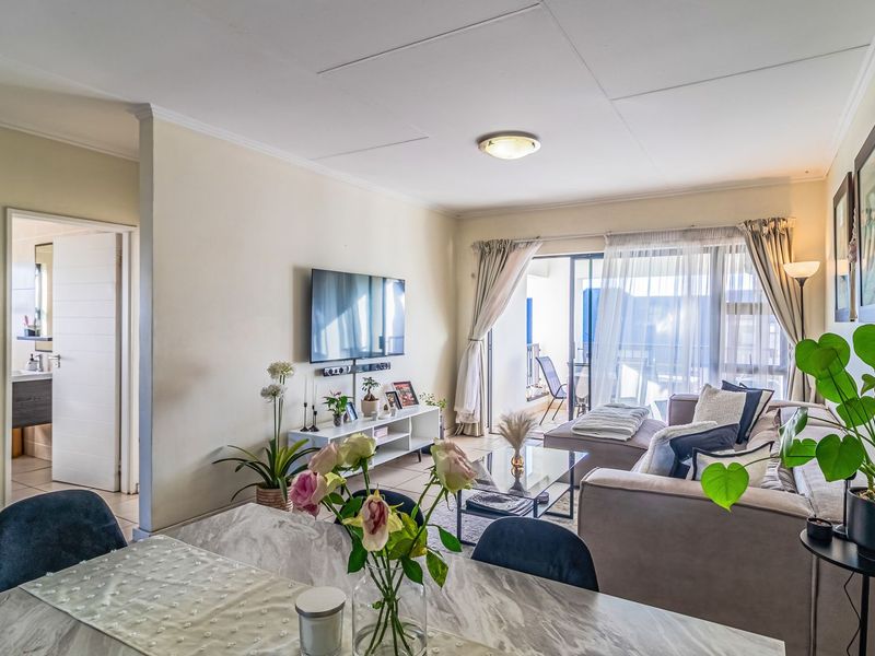 An open-plan living area featuring tiled flooring, coved ceilings, and a large sliding glass door providing access to an outdoor patio space.