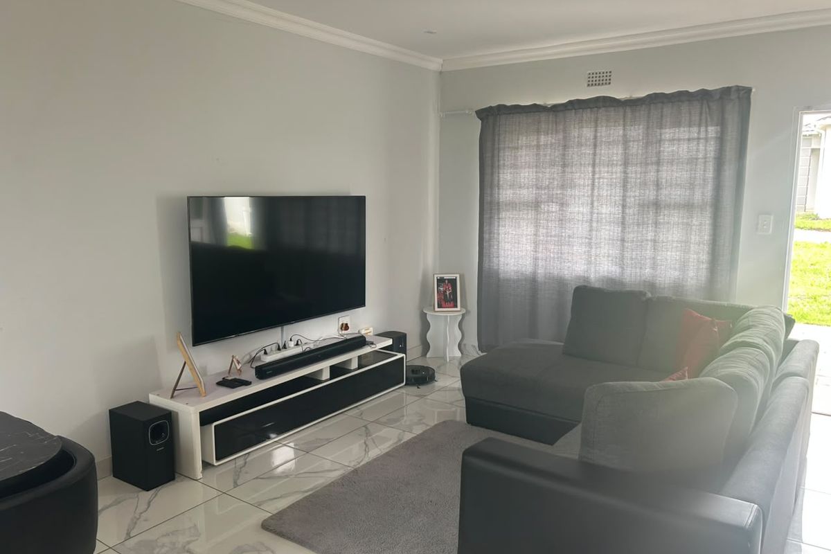 A well-maintained living room featuring modern marble-look floor tiles, crown molding, and neutral wall finishes, providing a clean and contemporary living space.