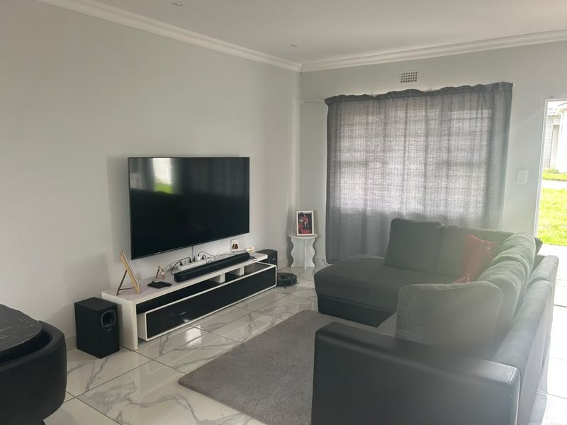 A well-maintained living room featuring modern marble-look floor tiles, crown molding, and neutral wall finishes, providing a clean and contemporary living space.