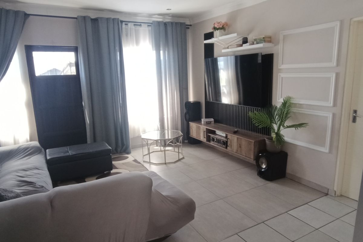 A comfortable living room featuring tiled flooring, recessed lighting, and a modern built-in media wall unit with integrated shelving.