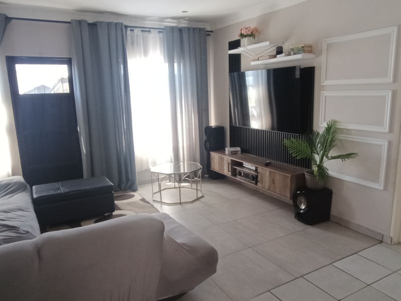 A comfortable living room featuring tiled flooring, recessed lighting, and a modern built-in media wall unit with integrated shelving.