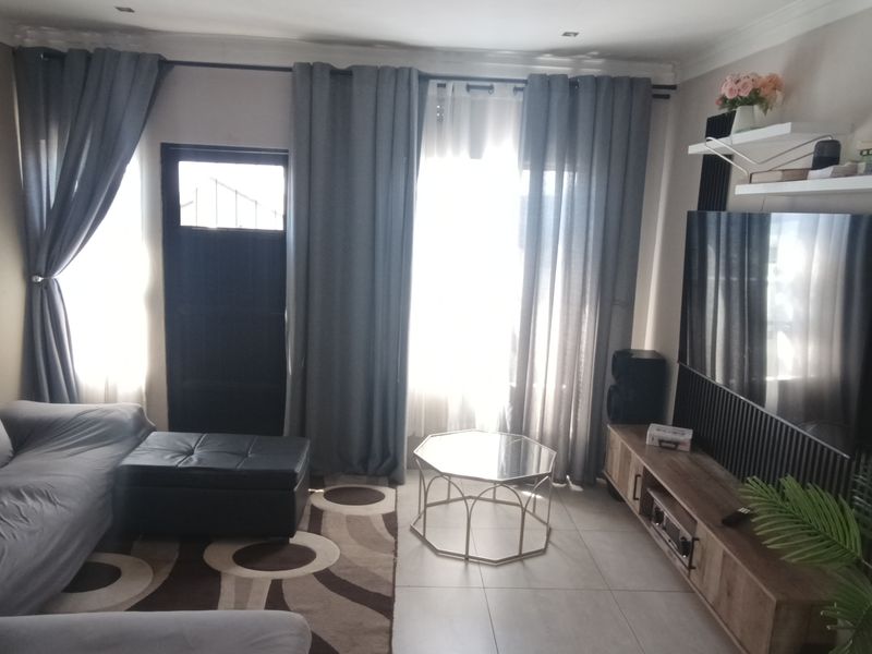 A comfortable living room featuring tiled flooring, recessed lighting, and a wall-mounted air conditioning unit, providing a functional and well-maintained space.