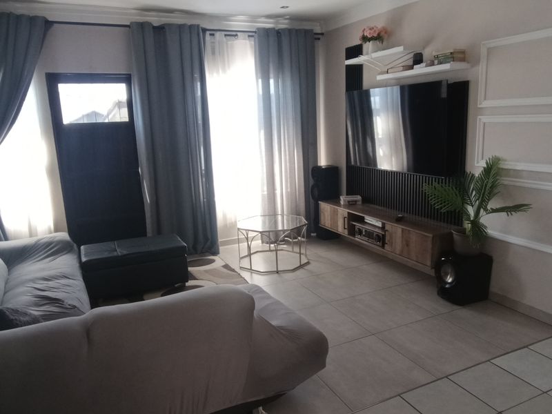 A well-maintained living room featuring tiled flooring, a built-in media console, and decorative wall paneling, creating a comfortable and functional living space.