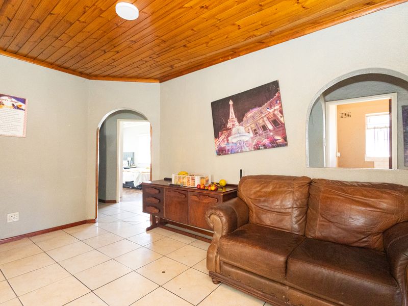 Living area featuring a timber tongue and groove ceiling, ceramic tiled flooring, and distinctive arched architectural openings connecting to adjacent rooms.