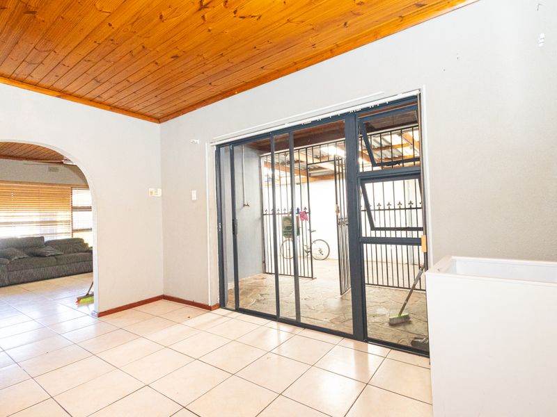 Living area featuring a timber ceiling, ceramic tiled flooring, and an aluminium sliding door leading to an enclosed patio area.