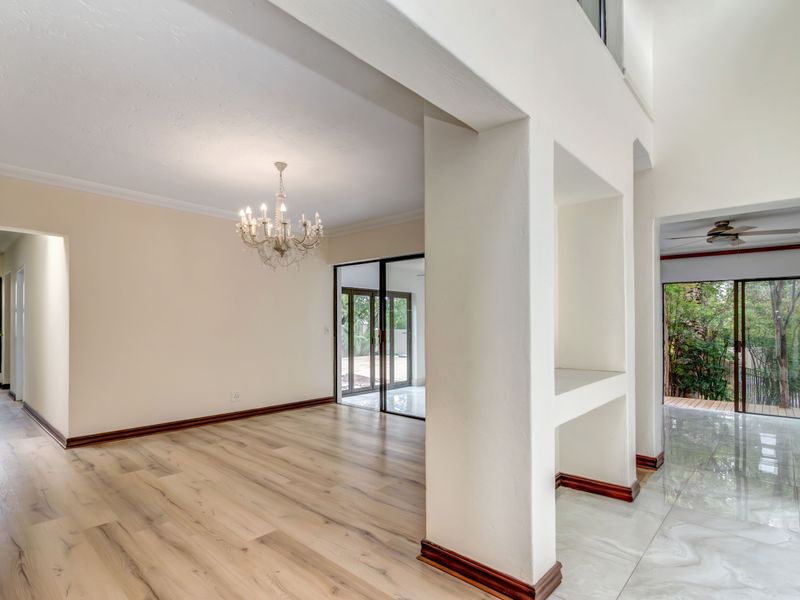 Spacious open-plan living area featuring a mix of laminate and tiled flooring, built-in shelving, and large sliding glass doors leading to the outdoors.