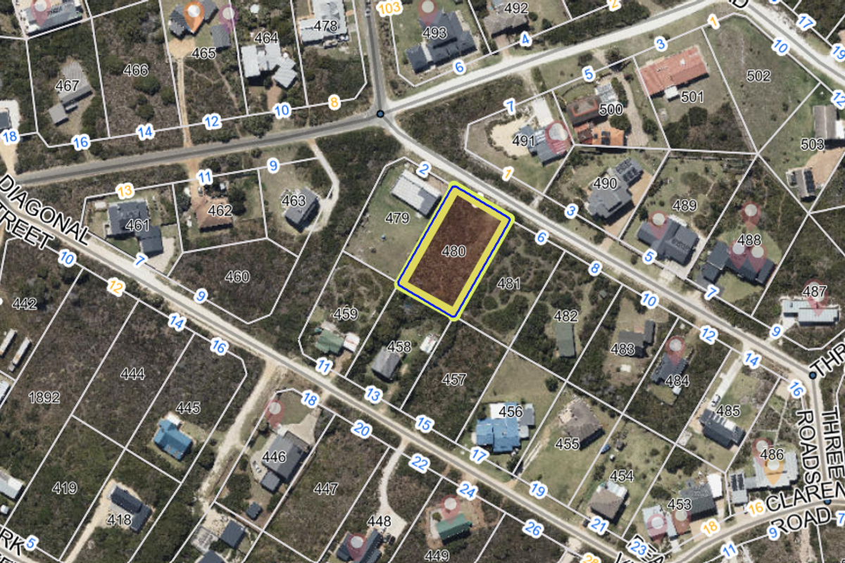 Aerial view of a vacant residential land plot in a developed coastal neighborhood, highlighting the property boundaries and surrounding infrastructure.