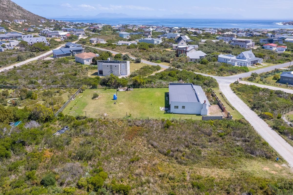 Aerial view of a vacant residential plot featuring established lawn, perimeter fencing, and convenient access to local gravel roads in a coastal setting.