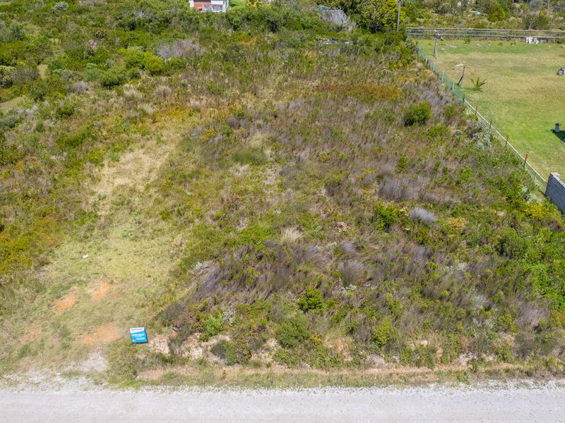 An aerial view of a vacant residential plot featuring natural vegetation and boundary fencing, ready for development.