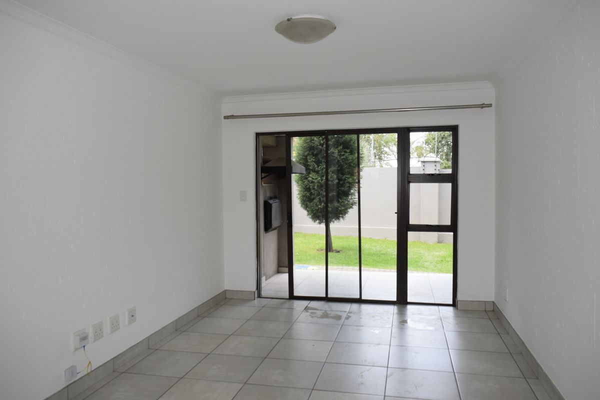 An empty living room featuring tiled flooring and a large sliding glass door providing direct access to the outdoor patio area.