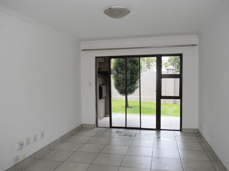 An empty living room featuring tiled flooring and a large sliding glass door providing direct access to the outdoor patio area.