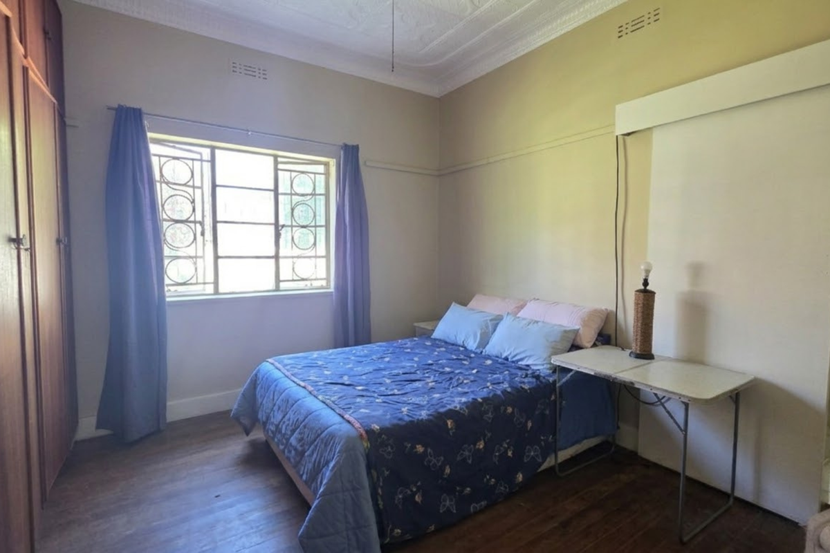 A bedroom featuring original timber flooring, ornate ceiling cornices, and built-in wooden cupboards, offering a classic foundation for modern updates.