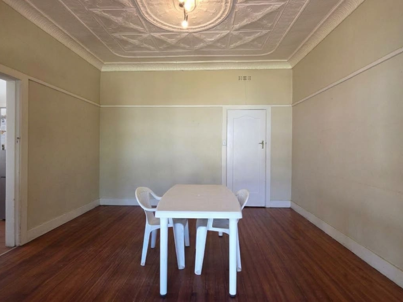 Spacious dining room featuring original pressed metal ceilings, hardwood flooring, and classic picture rails, offering a bright and versatile living space.