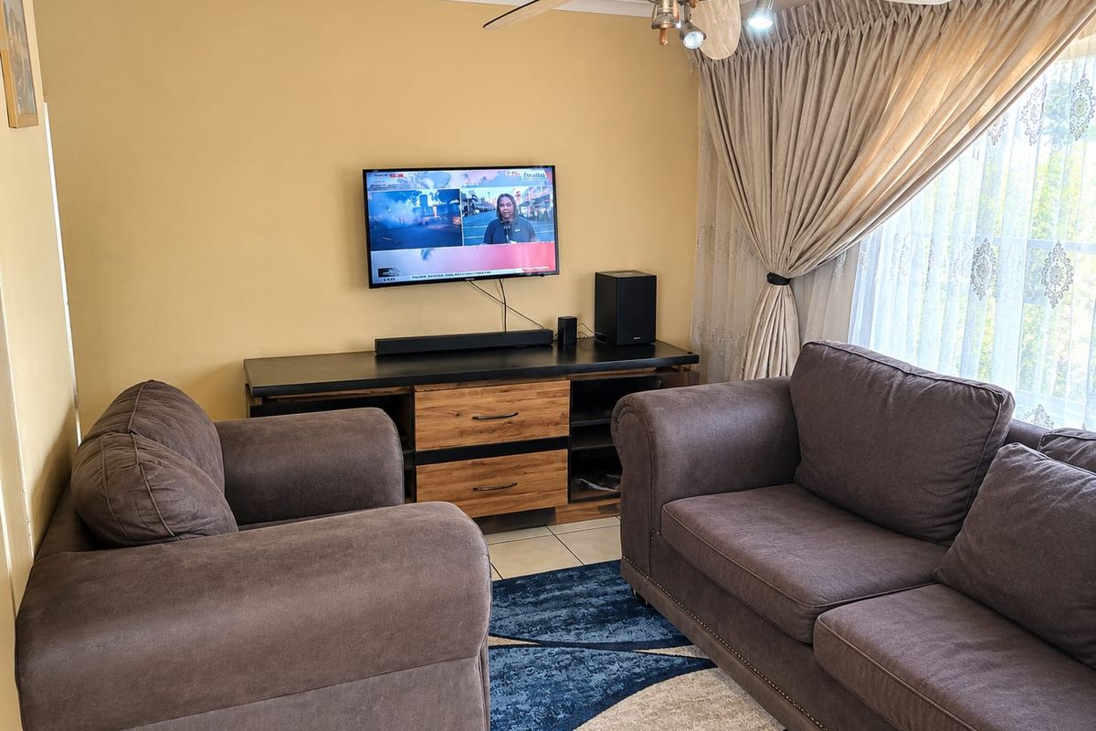 A comfortable living room featuring tiled flooring and a ceiling fan, providing a functional space for relaxation.