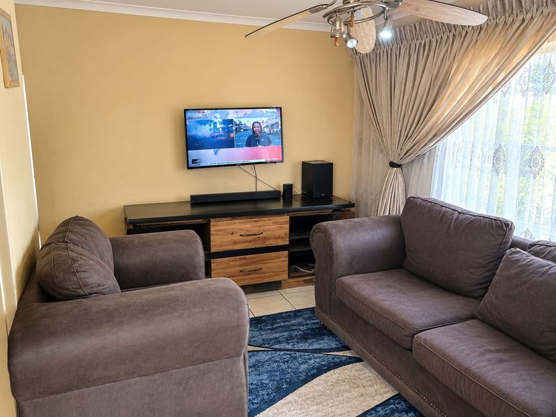 A comfortable living room featuring tiled flooring and a ceiling fan, providing a functional space for relaxation.