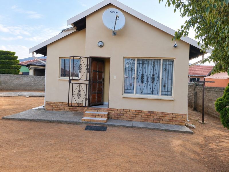 Front elevation of a detached house featuring a brick plinth, security gate, and satellite dish installation.