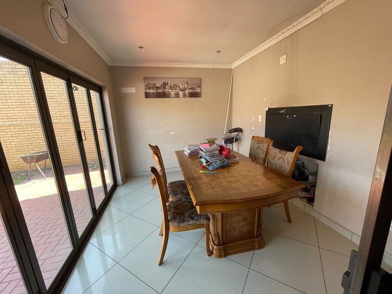 Dining room featuring large sliding glass doors, tiled flooring, and crown molding. The space requires cosmetic wall repairs and updates to improve its overall condition.