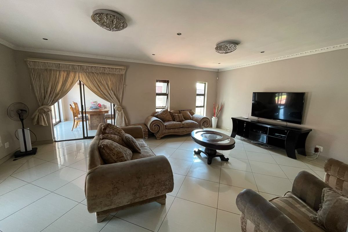 Spacious living room featuring large format floor tiles, recessed lighting, crown molding, and sliding glass doors leading to an outdoor patio area.