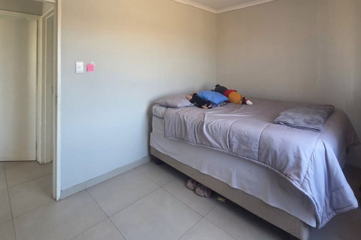 A simple bedroom featuring neutral wall paint and tiled flooring, providing a functional and blank canvas for personalization.