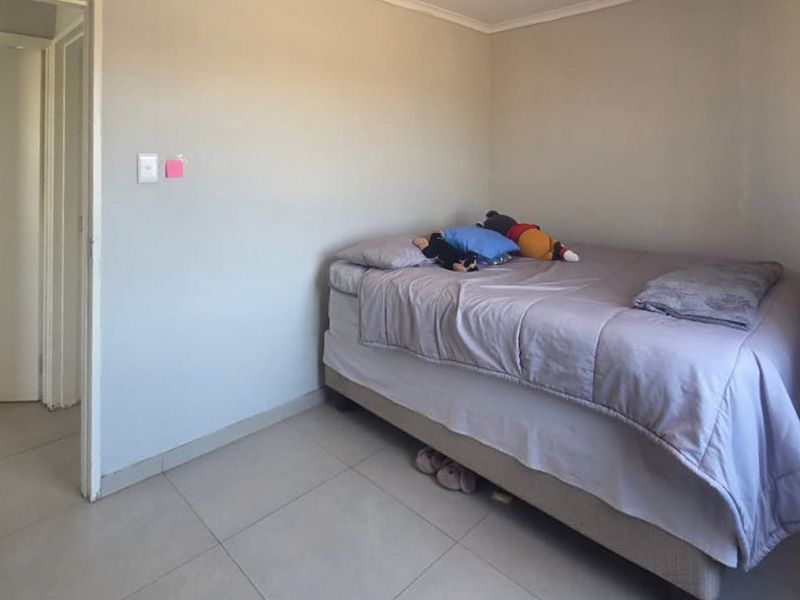 A simple bedroom featuring neutral wall paint and tiled flooring, providing a functional and blank canvas for personalization.
