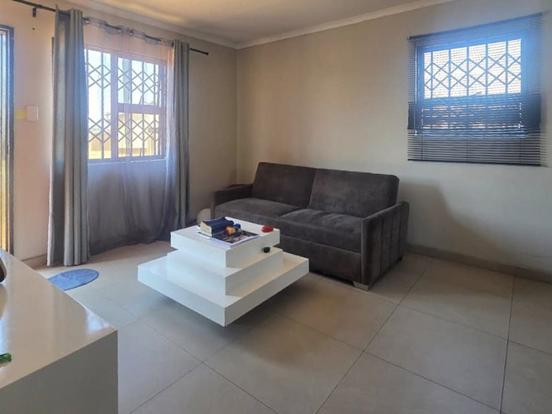 A functional living room featuring tiled flooring, security bars on the windows, and venetian blinds, offering a neutral base for personalization.
