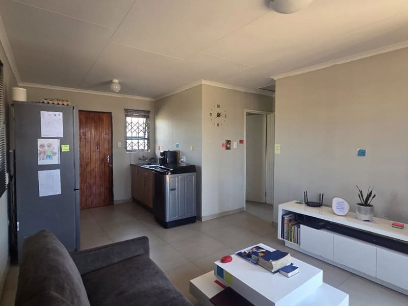 Open plan living area featuring tiled flooring and a compact kitchen corner with built-in cabinetry and sink.