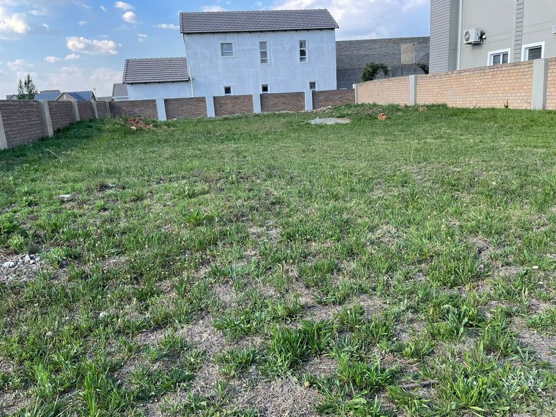 A vacant residential plot featuring a grass lawn enclosed by perimeter brick boundary walls.
