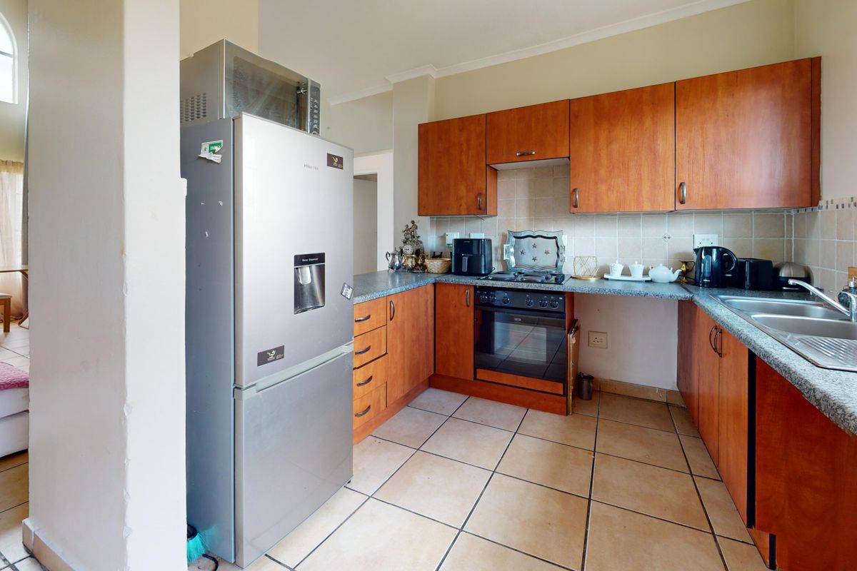 A functional kitchen featuring wooden cabinetry, laminate countertops, a built-in oven, and tiled flooring, offering a practical layout for daily meal preparation.