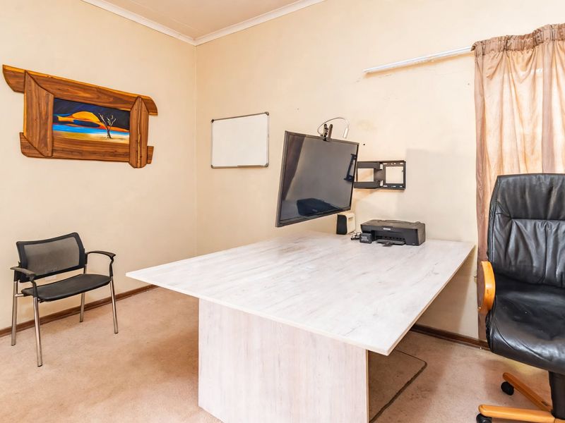 A functional home office space featuring carpeted flooring and a wall-mounted television bracket, offering a dedicated area for work or study.