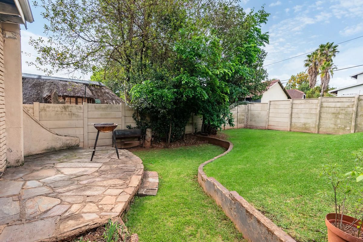A private rear garden featuring a flagstone patio area, a lawn, and a precast concrete boundary wall.