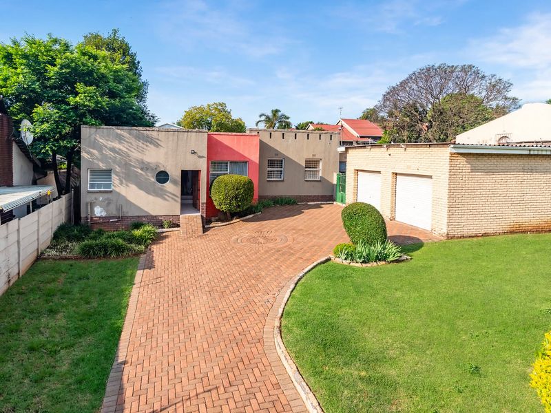 Front exterior view of a house featuring a paved driveway, double garage, and a well-maintained lawn area.