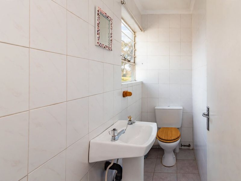 A compact bathroom featuring tiled walls and flooring, a pedestal basin, and a standard toilet.