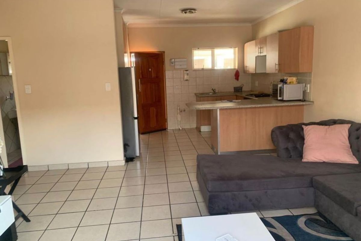 Open-plan living area featuring a functional kitchen with breakfast bar and tiled flooring throughout, offering a practical layout for modern apartment living.