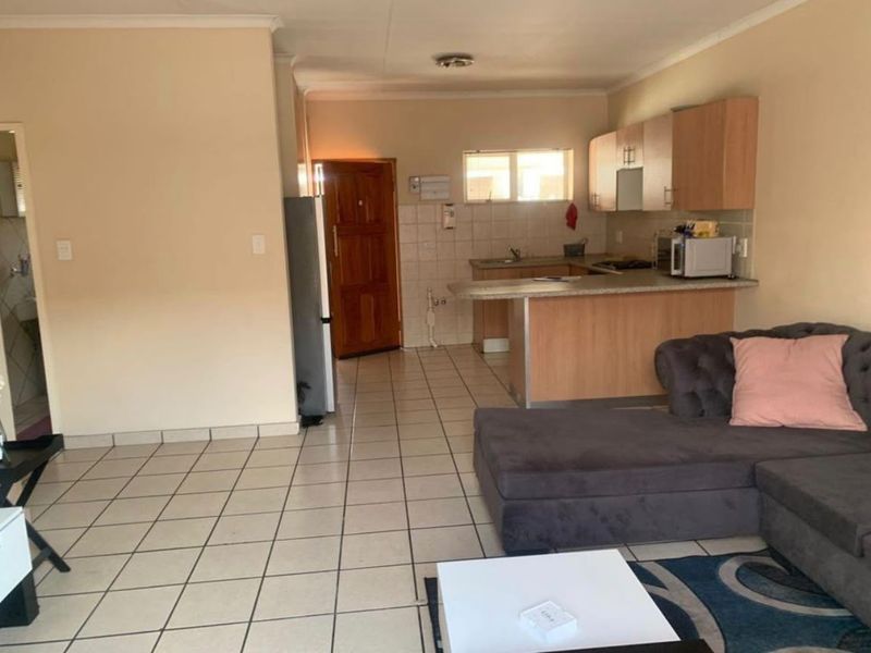 Open-plan living area featuring a functional kitchen with breakfast bar and tiled flooring throughout, offering a practical layout for modern apartment living.